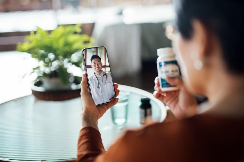 Paciente mostrando medicamento a médico mediante llamada virtual por telesalud.