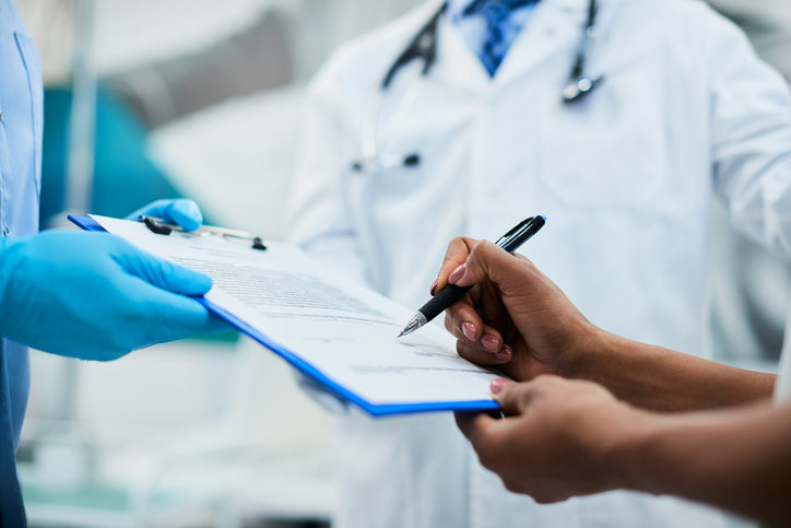 Close-up of woman signing medical agreement at doctor's office.